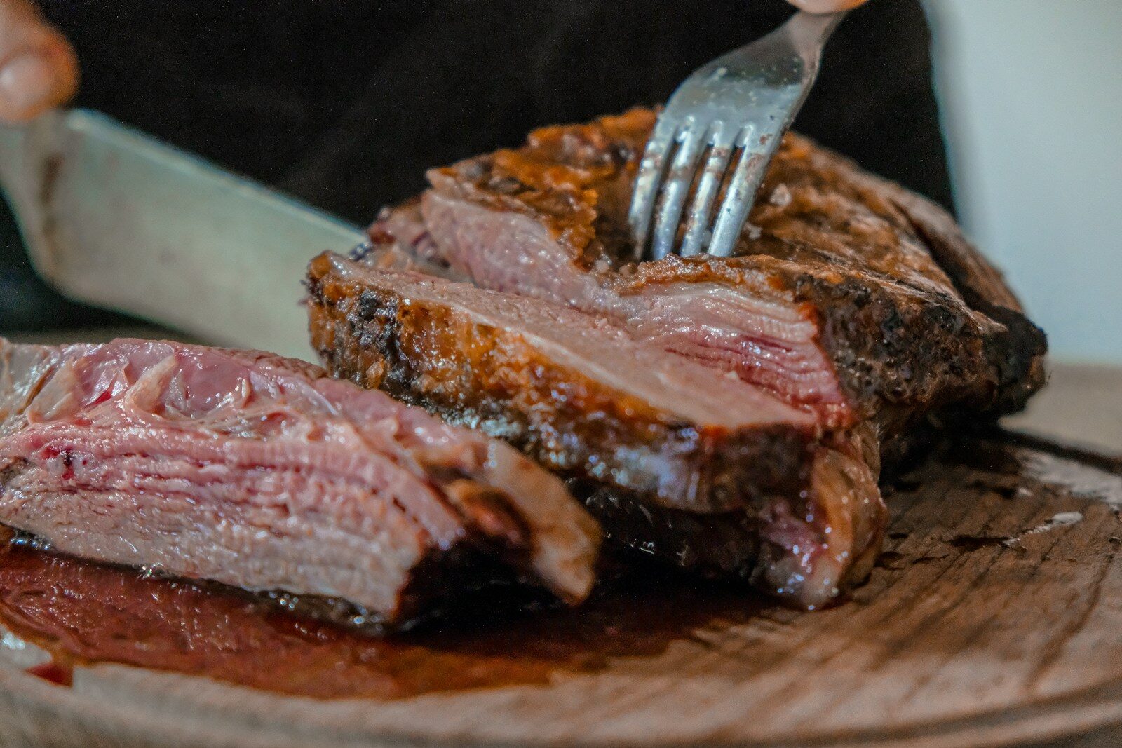 Nos produits person slicing a meat on brown wooden board